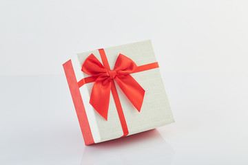 White gift box with red ribbon bow on white