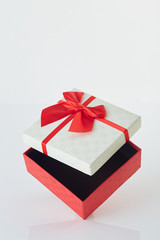 White gift box with red ribbon bow on white