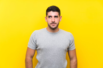Young handsome man over isolated yellow background standing and looking to the side