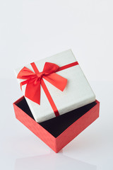 White gift box with red ribbon bow on white