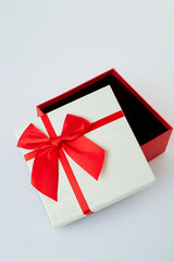 White gift box with red ribbon bow on white