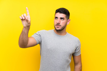Young handsome man over isolated yellow background touching on transparent screen