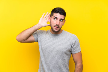 Young handsome man over isolated yellow background listening something