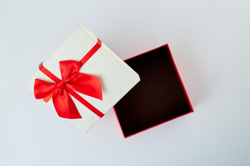 White gift box with red ribbon bow on white