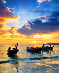 Traditionelle thailändische Boote am Strand bei Sonnenuntergang
