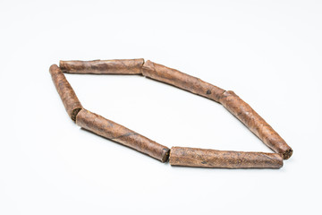 Obraz premium Small twisted rhombus cigars on white background.