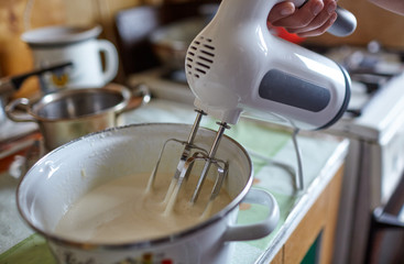 Fototapeta premium Woman prepares dough by mixing ingredients in a pan with a mixer