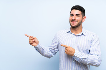 Caucasian handsome man over isolated blue background pointing finger to the side