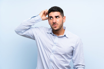 Caucasian handsome man over isolated blue background having doubts and with confuse face expression