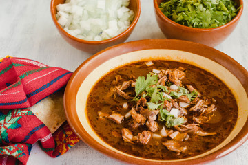 Birria de res on a white table, with all the ingredients used to prepare it. Typical recipe from Mexico