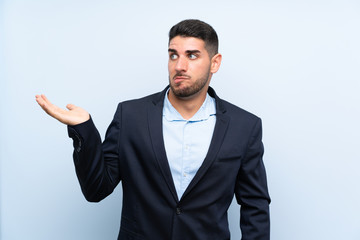 Handsome man over isolated blue background unhappy for not understand something