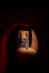 Woman in dress looking at the light in a corridor of the ancient city of Benhadou located in Morocco