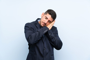 Handsome man over isolated blue background making sleep gesture in dorable expression