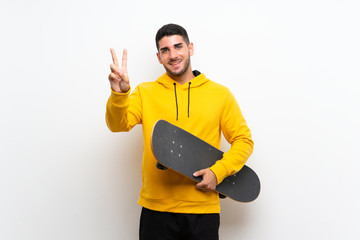 Handsome young skater man over isolated white wall smiling and showing victory sign © luismolinero