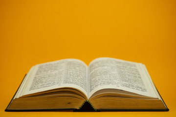 Fototapeta na wymiar Open Holy Bible on a yellow background table. Religion concept.