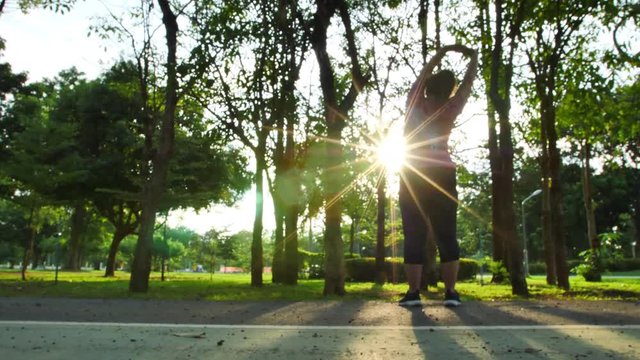 Slow Motion Rear view of women asian Warm up, stretch and run exercise in the park and evening sun. Good health and exercise