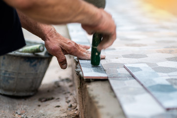 Close up of handyman affixing adhesive grout to get tiled concrete before the front door.