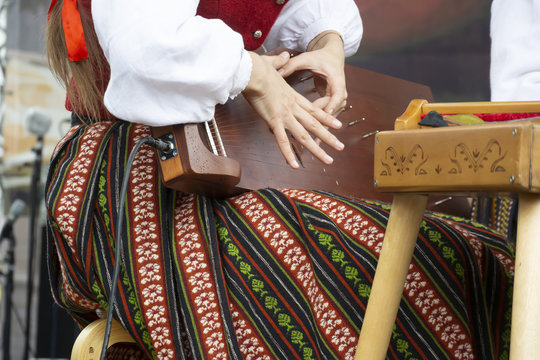 A young girl plays the kokle string instrument