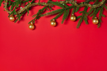 Christmas border made of spruce branches and golden balls. Christmas red background. Flat lay, top view, copy space. Christmas concept