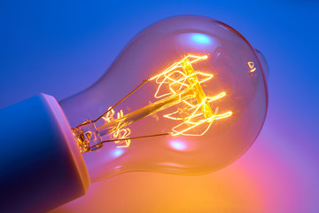 Alte Glühlampe mit orange leuchtendem Glühwendel.