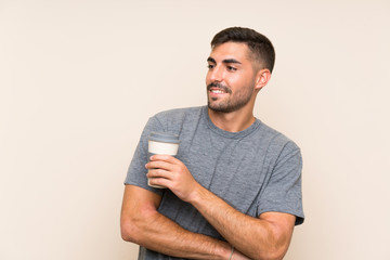 Handsome man with beard holding a take away coffee over isolated background