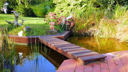 malerische Holzbrücke spannt sich über den Gartenteich im sonnigem Herbst