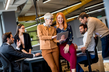 Happy business women working together online on a digital tablet at the office