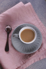 A small cup of coffee with milk on a pink napkin