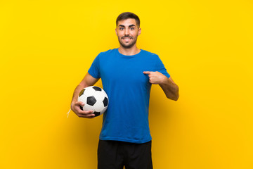 Young handsome football player man over isolated yellow wall with surprise facial expression