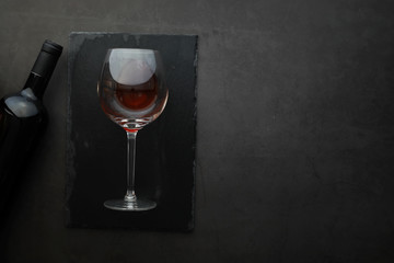 Wine glass and black wine bottle. Nuts cheese and tomatoes for snack.