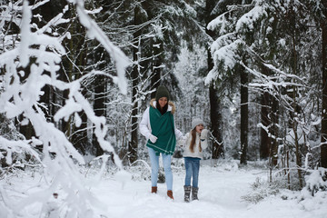 Young family for a walk. Mom and daughter are walking in a winter park.