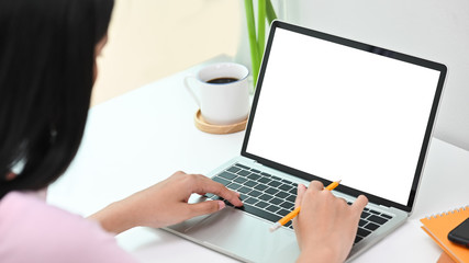 Woman using laptop computer with blank screen in creative workspace.