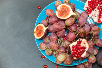 Grapes, figs and pomegranate on a dark background