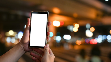 Mockup smartphone on hands with empty screen and bokeh on blur night city background.