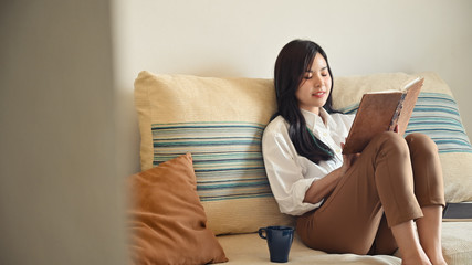 Young woman relaxing at home with reading a book.