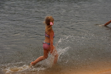 GIRL RUNS ALONG THE SHORE OF THE LAKE