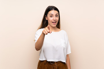 Young brunette woman over isolated background surprised and pointing front