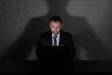 Hacker in black mask and hood at the table