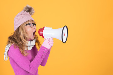 adult woman with warm and winter clothes with megaphone in color background