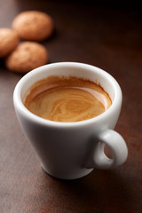 Cup of coffee with amaretti (Italian biscuits) on rustic wooden background. Close up.