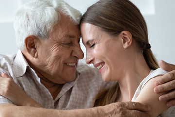 Loving grandfather touch foreheads of adult granddaughter relative people hugging