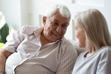 80s man sitting on couch talking with middle aged woman