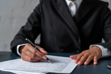 Fototapeta premium Hands of African American businesswoman working with documents at blurred office desk. Concept of legal and paperwork