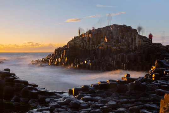 Long Exposure Sunset At Giant Causeway With Shadows Of Moving People Standing On Rocks Creating A Ghost Effect