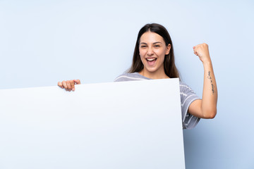 Fototapeta premium Young brunette woman over isolated blue background holding an empty white placard for insert a concept