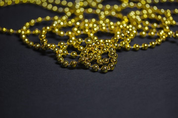 Gold Christmas garland on a black background. Top view. Copy space.Christmas frame for text. Black Christmas background with lights and bokeh.