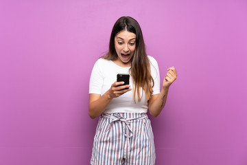 Young woman over isolated purple background surprised and sending a message