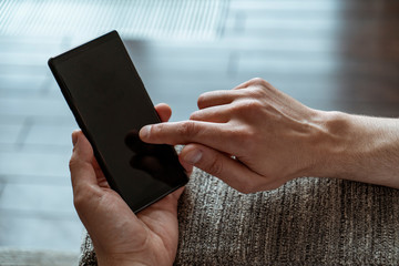 Top view of man hands tapping smartphone screen at home or in blurry office. Concept of web surfing and internet
