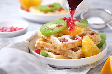 delicate waffles with fruits and berries and fruit syrup
