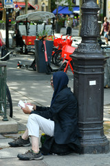 a man writes while sitting on the ground near a pillar